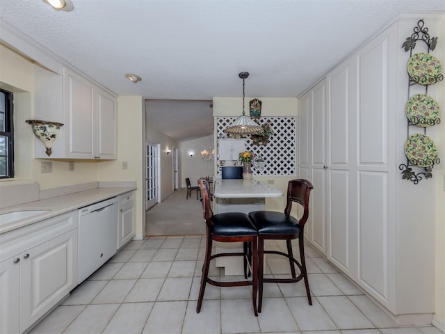 kitchen featuring a notable chandelier, pendant lighting, white cabinetry, light countertops, and dishwasher