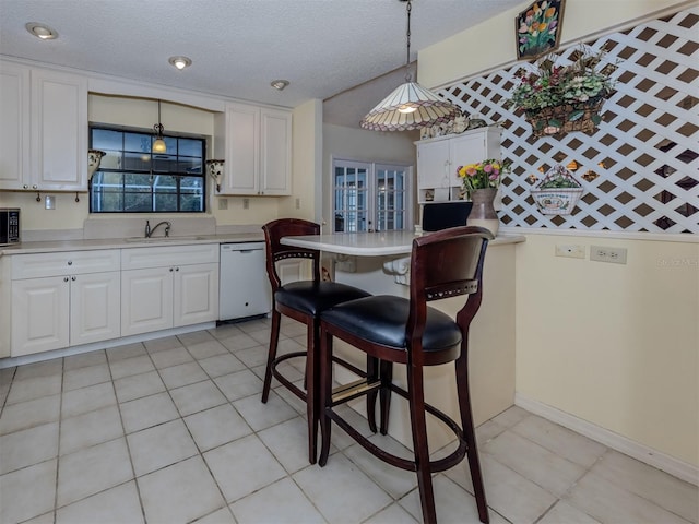 kitchen featuring white dishwasher, a sink, light countertops, white cabinetry, and a kitchen breakfast bar