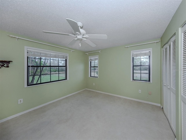 unfurnished bedroom with baseboards, carpet flooring, a textured ceiling, and a ceiling fan