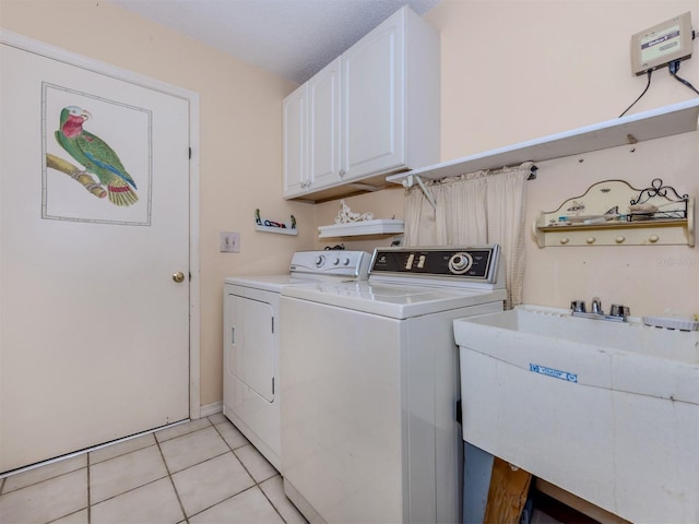 washroom with a sink, cabinet space, light tile patterned flooring, and washer and dryer