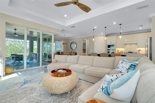 living area with visible vents, light wood-type flooring, a tray ceiling, recessed lighting, and crown molding