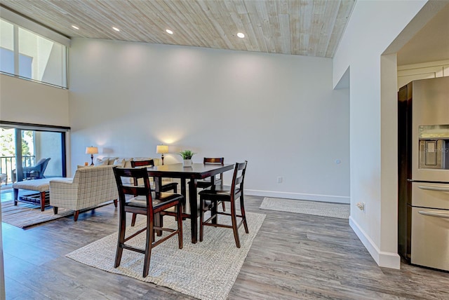 dining room featuring a high ceiling, recessed lighting, wood finished floors, and baseboards