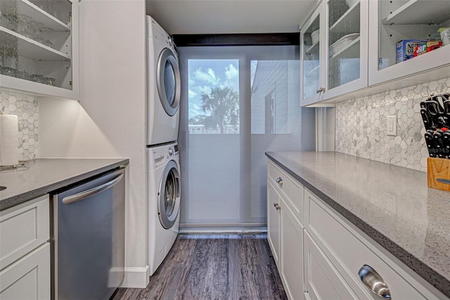 washroom featuring laundry area, dark wood-type flooring, and stacked washer / dryer