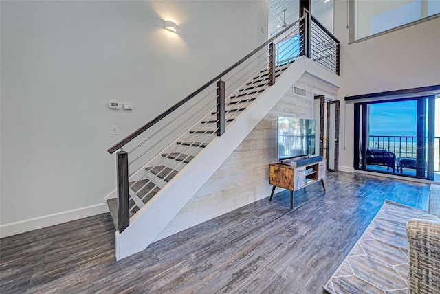 stairs featuring a high ceiling, baseboards, and wood finished floors