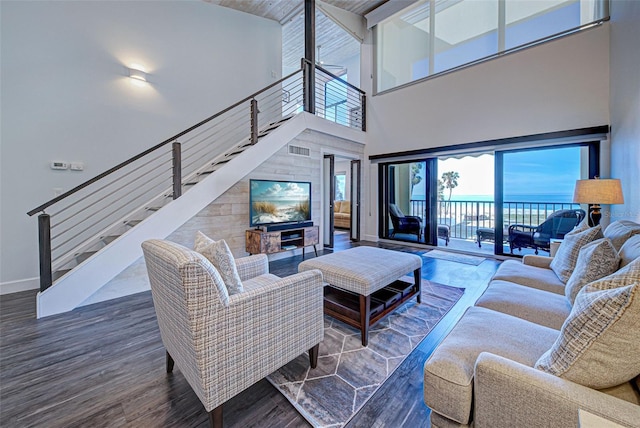 living room featuring visible vents, stairway, baseboards, and wood finished floors