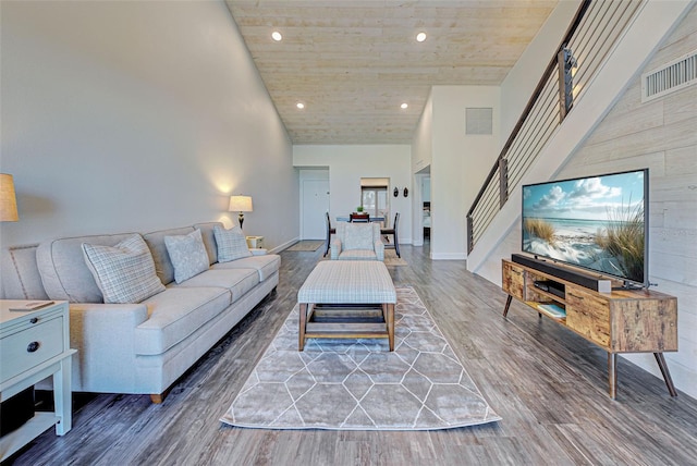 living area with visible vents, stairway, wood finished floors, a high ceiling, and recessed lighting