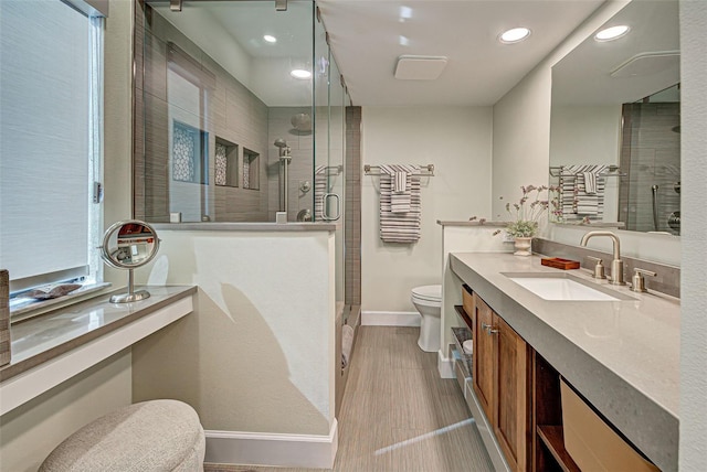 bathroom featuring a stall shower, baseboards, vanity, and toilet