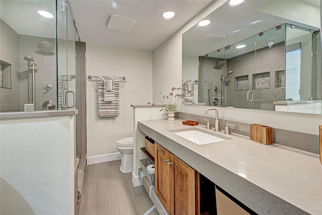 bathroom featuring a stall shower, baseboards, vanity, and toilet