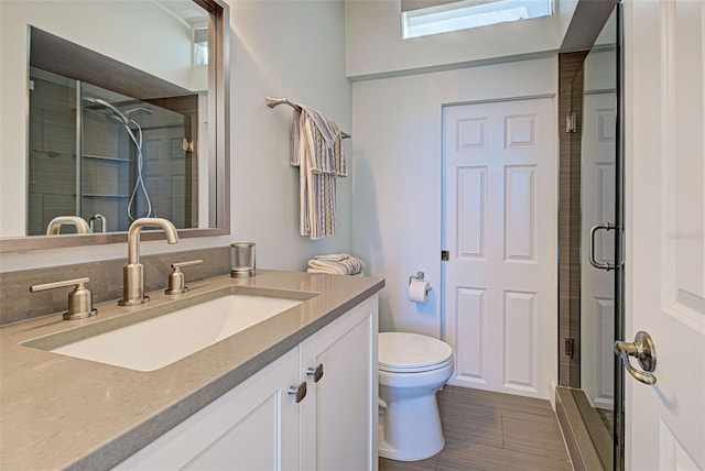 bathroom with toilet, a shower stall, wood tiled floor, and vanity