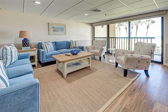 living area featuring a paneled ceiling, visible vents, and wood finished floors