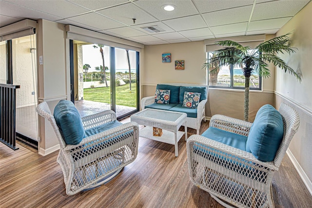 interior space with a paneled ceiling, baseboards, visible vents, and wood finished floors