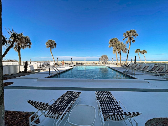 community pool with a patio area and fence