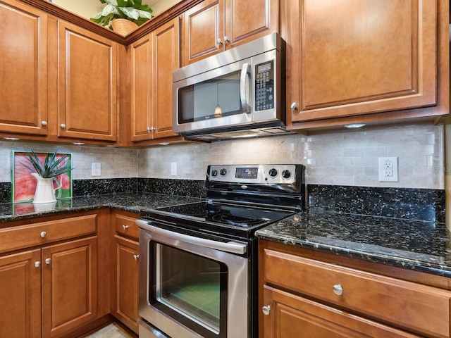 kitchen with stainless steel appliances, dark stone counters, brown cabinetry, and backsplash