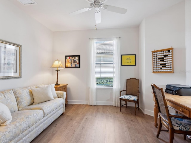 living room featuring light wood-type flooring, ceiling fan, and baseboards