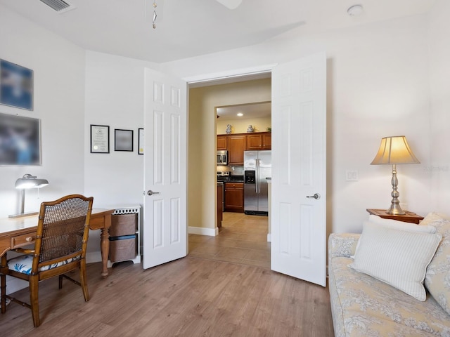 office with light wood-style flooring, visible vents, and baseboards