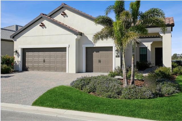 mediterranean / spanish house featuring decorative driveway, an attached garage, and stucco siding