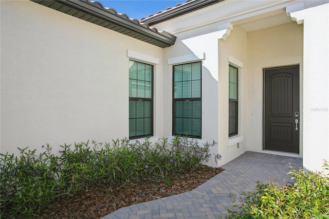 property entrance featuring a tile roof and stucco siding