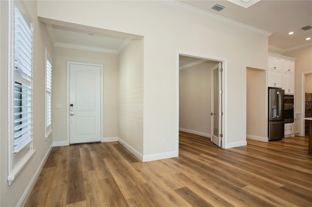 interior space with ornamental molding, visible vents, and wood finished floors