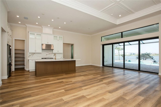 kitchen with stainless steel fridge, open floor plan, light countertops, under cabinet range hood, and white cabinetry