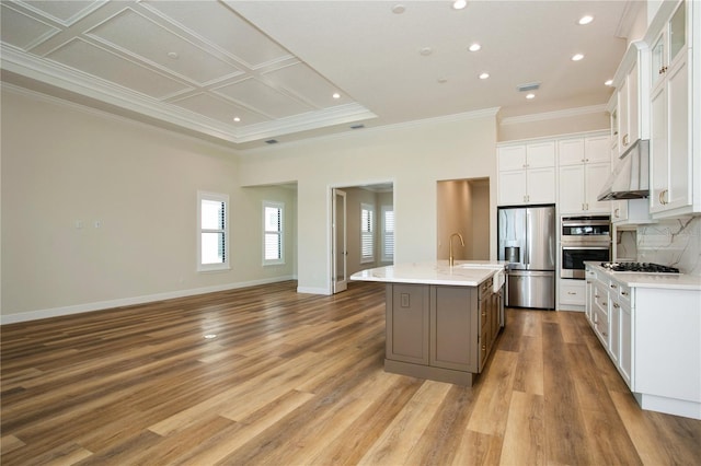 kitchen with baseboards, decorative backsplash, an island with sink, appliances with stainless steel finishes, and light countertops