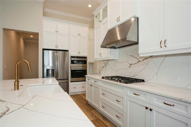 kitchen with ornamental molding, appliances with stainless steel finishes, a sink, and under cabinet range hood