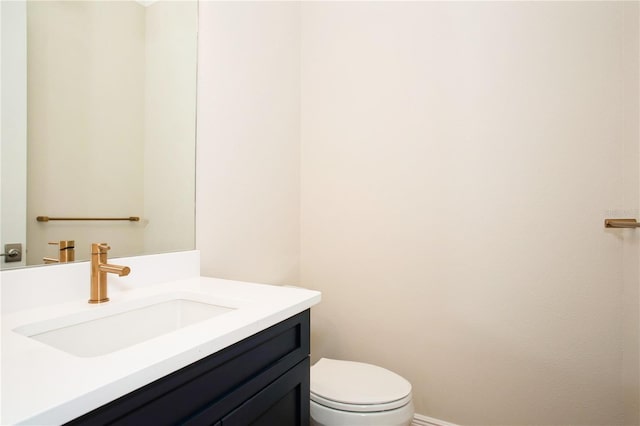 bathroom with baseboards, vanity, and toilet