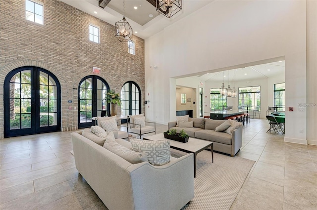 living room featuring french doors, a notable chandelier, recessed lighting, a towering ceiling, and baseboards