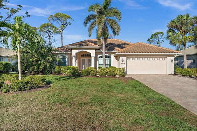 mediterranean / spanish-style house with an attached garage, a tiled roof, decorative driveway, stucco siding, and a front yard