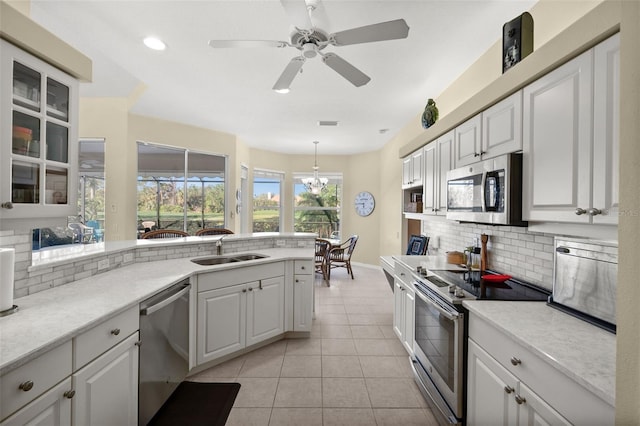 kitchen with decorative backsplash, light countertops, stainless steel appliances, a sink, and light tile patterned flooring