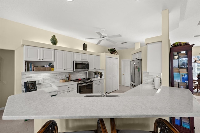 kitchen with appliances with stainless steel finishes, a breakfast bar, a peninsula, and open shelves