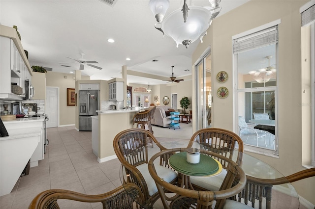 dining space with light tile patterned floors, ceiling fan with notable chandelier, baseboards, and recessed lighting