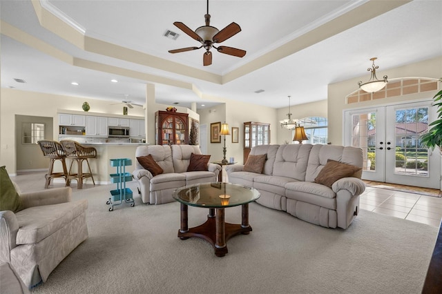 living area with a tray ceiling, french doors, light tile patterned floors, visible vents, and ornamental molding