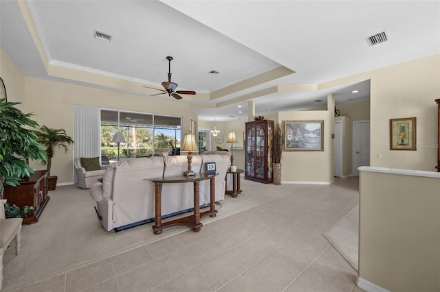 living room featuring ceiling fan, ornamental molding, a raised ceiling, and visible vents