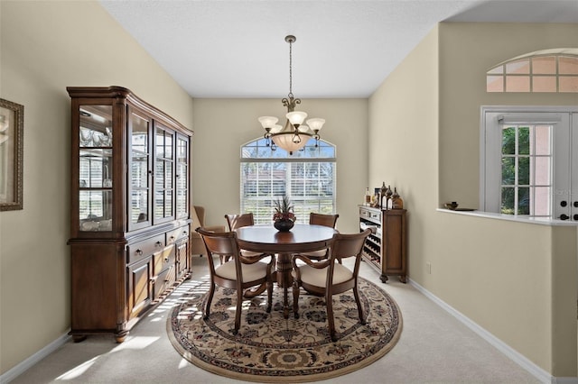 dining area featuring an inviting chandelier, baseboards, and light colored carpet