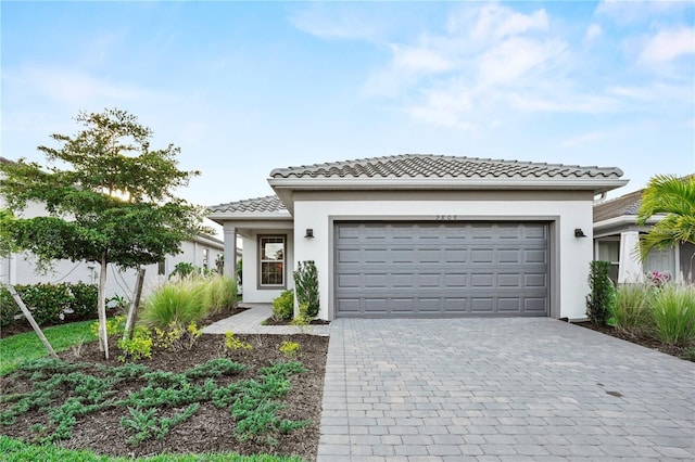 view of front facade with an attached garage, a tiled roof, decorative driveway, and stucco siding