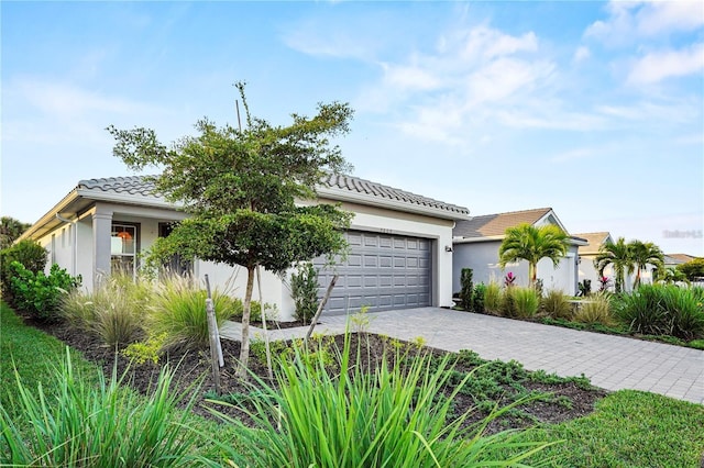 view of front of property with a garage, a tiled roof, decorative driveway, and stucco siding