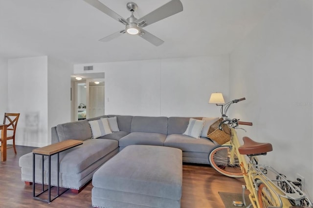 living area with a ceiling fan, visible vents, and wood finished floors