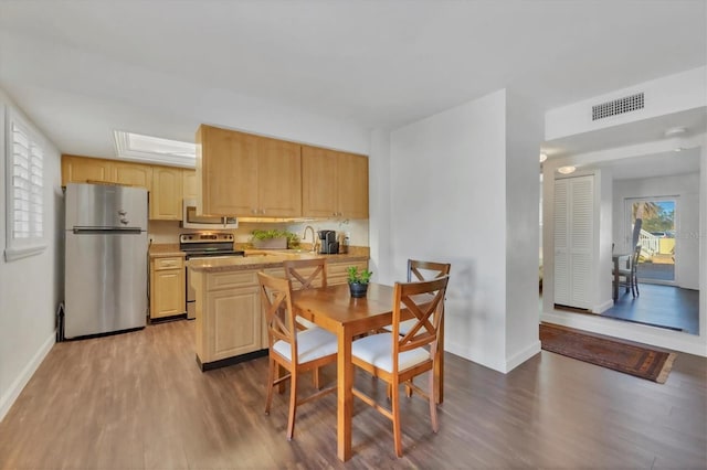 kitchen featuring light countertops, visible vents, light brown cabinetry, appliances with stainless steel finishes, and wood finished floors