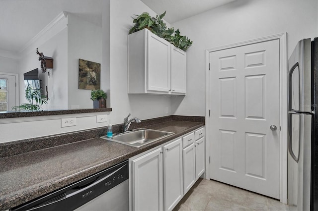 kitchen with dark countertops, freestanding refrigerator, white cabinetry, a sink, and dishwasher