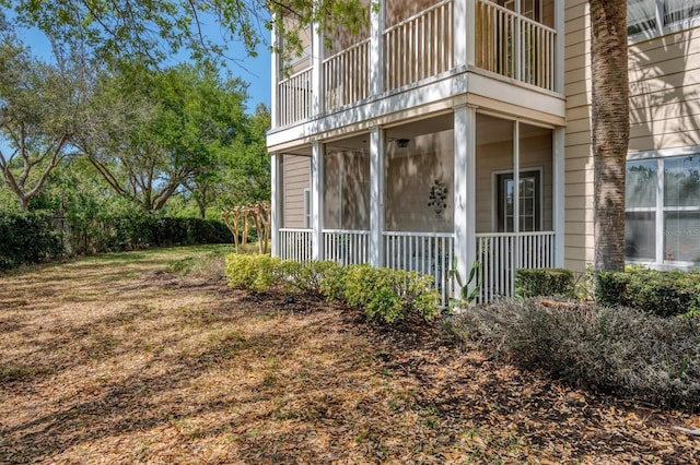 view of home's exterior with a sunroom and a balcony