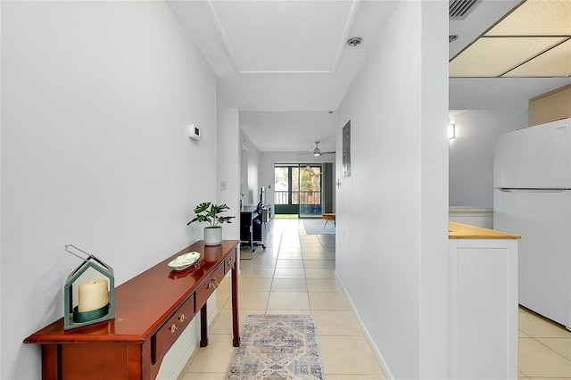 hallway with light tile patterned floors, visible vents, and baseboards