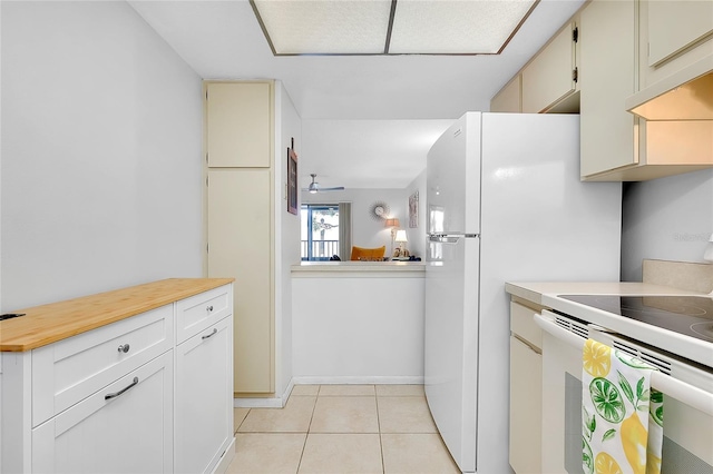 kitchen with white electric stove, light tile patterned floors, under cabinet range hood, butcher block counters, and a ceiling fan