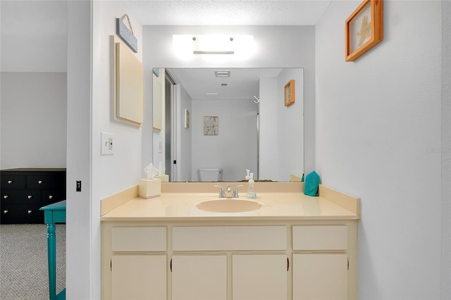 bathroom with a textured ceiling, vanity, and toilet