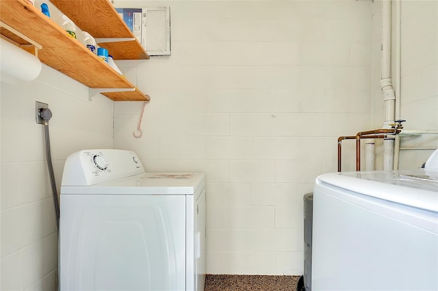 washroom with laundry area, washer and clothes dryer, and concrete block wall