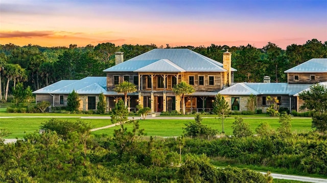 view of front of house featuring metal roof, a front lawn, and a chimney