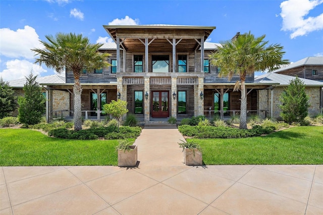 view of front of property featuring metal roof, french doors, a front lawn, and stone siding