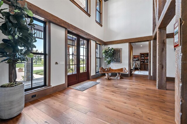 foyer entrance with french doors, hardwood / wood-style floors, and a high ceiling