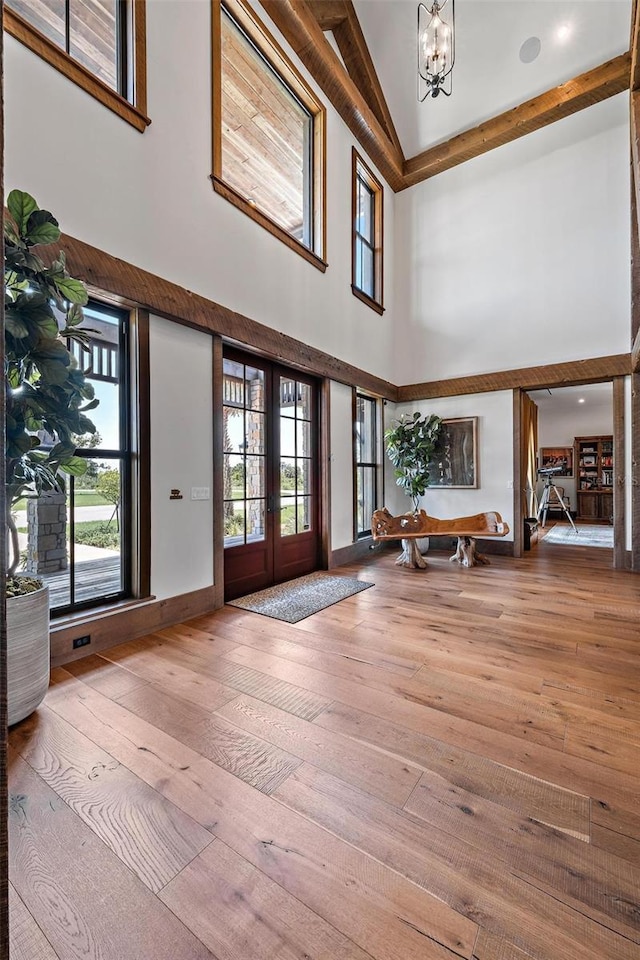 foyer entrance featuring a chandelier, french doors, a high ceiling, and hardwood / wood-style flooring