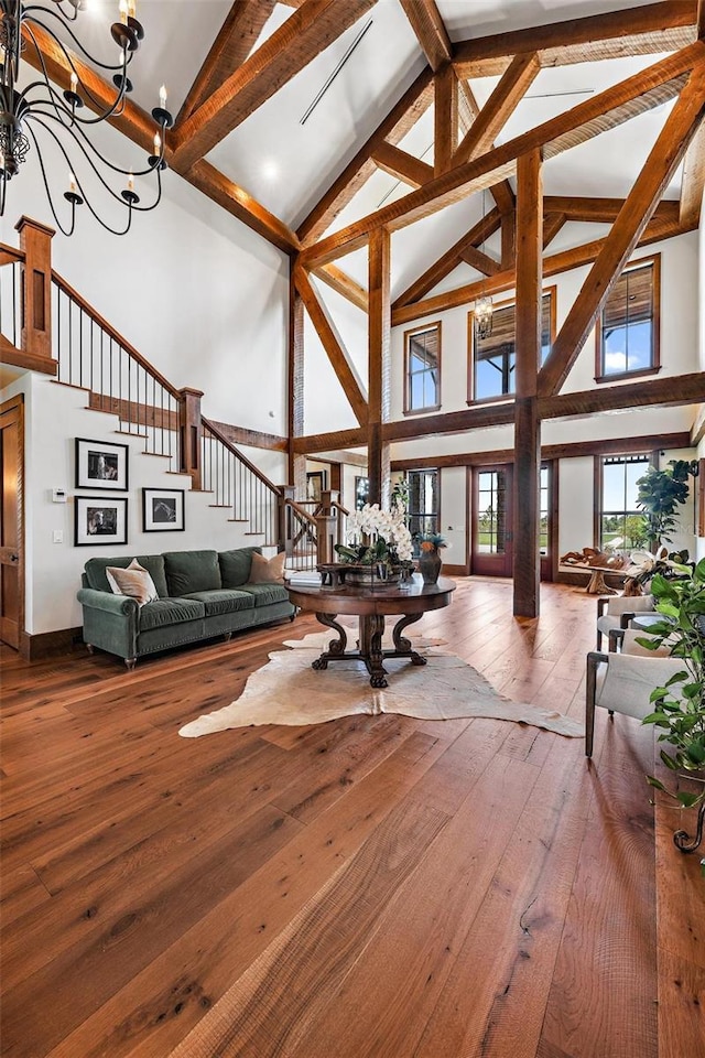 living area featuring beamed ceiling, stairway, hardwood / wood-style flooring, and an inviting chandelier