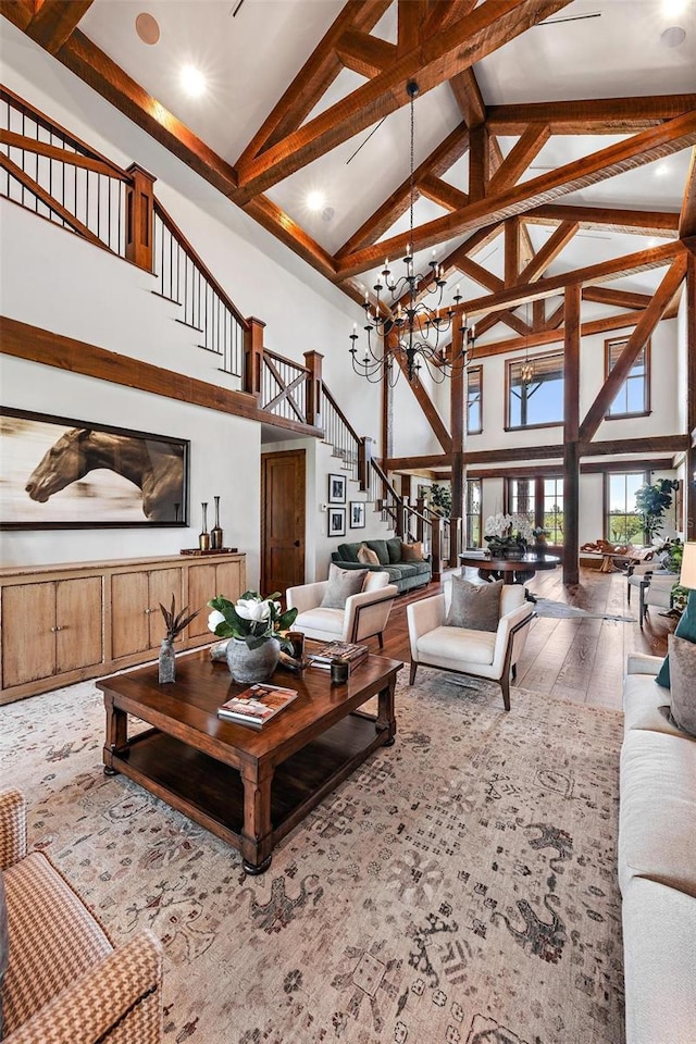 living room with wood-type flooring, stairway, a chandelier, and beamed ceiling